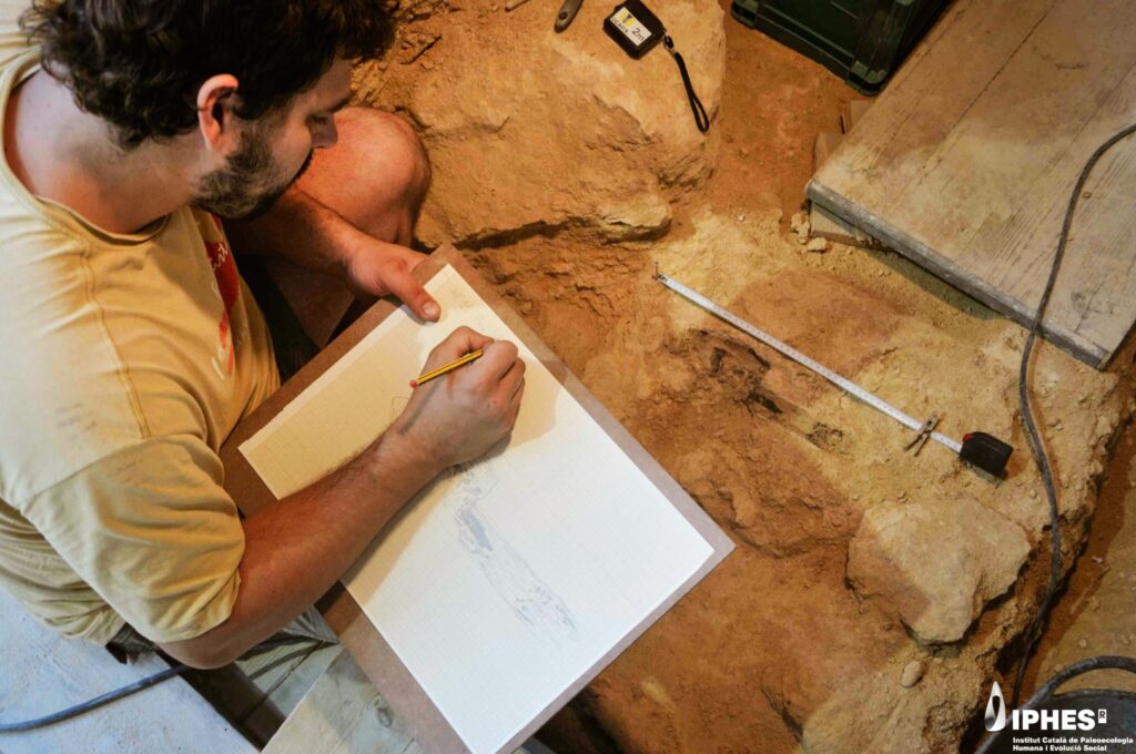 Treball de dibuix i registre durant l’excavació de l’objecte de fusta interpretat com una maça, procedent de l’Abric Romaní. Autoria: Gerard Campeny / IPHES-CERCA.